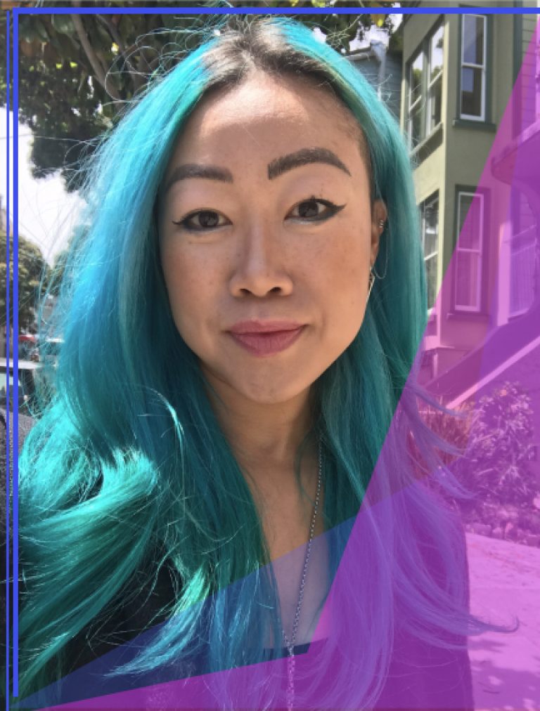 AAPI girl with teal hair smiling pleasantly with San Francisco Victorian Homes in the background
